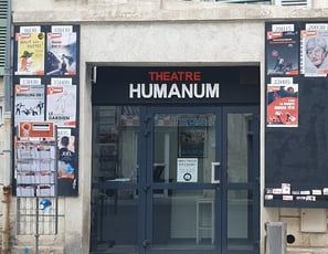 Photo de la façade du théâtre, composée de deux panneaux en bois pour les affiches et d'une porte vitrée au centre.