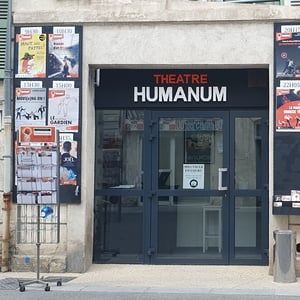 Photo de la façade du théâtre, composée de deux panneaux en bois pour les affiches et d'une porte vitrée au centre.
